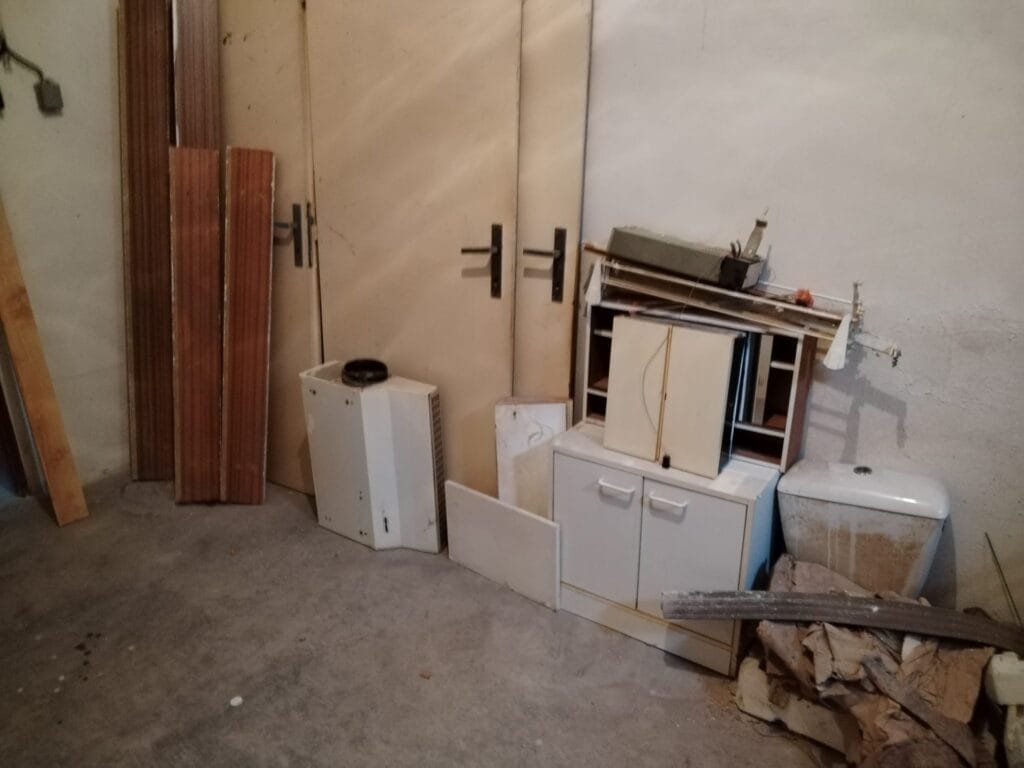 Zanedbaný sklep s nepotřebným nábytkem a materiály určenými k vyklízení.