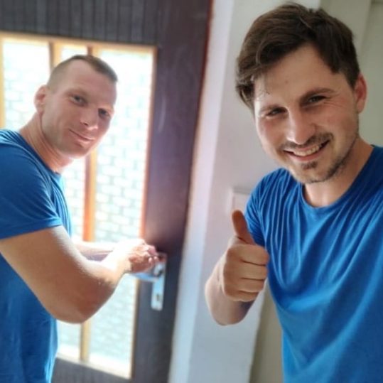 Dva muži v modrých tričkách při vyklízecích pracích se zdraví.