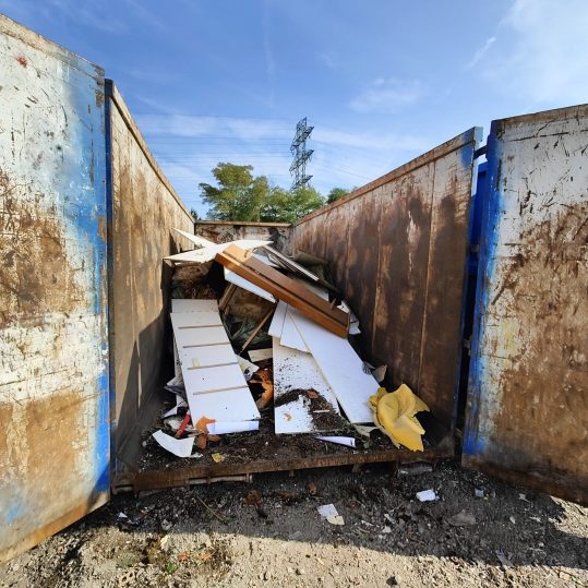 Velký kontejner naplněný stavebním odpadem a zbytky materiálů
